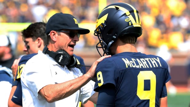 Michigan football coach Jim Harbaugh pumps up quarterback J.J. McCarthy on the sidelines